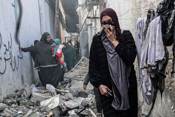 Люди пробираются по заваленному переулку после ночной израильской бомбардировки Рафаха на юге сектора Газа 25 февраля. - Sputnik Таджикистан