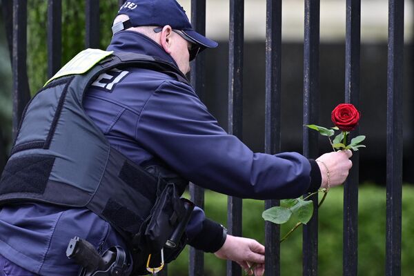 Сотрудник полиции возлагает цветы возле посольства России в Берлине. - Sputnik Таджикистан