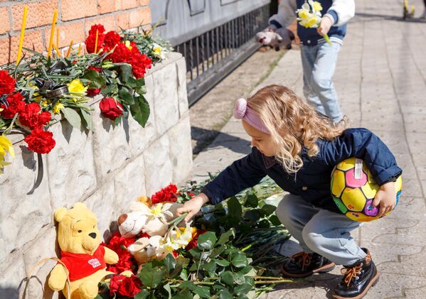 Девочка возлагает цветы к стихийному мемориалу возле российского консульства в Тирасполе во время акции в память о жертвах теракта в подмосковном &quot;Крокус сити холле&quot;. - Sputnik Таджикистан