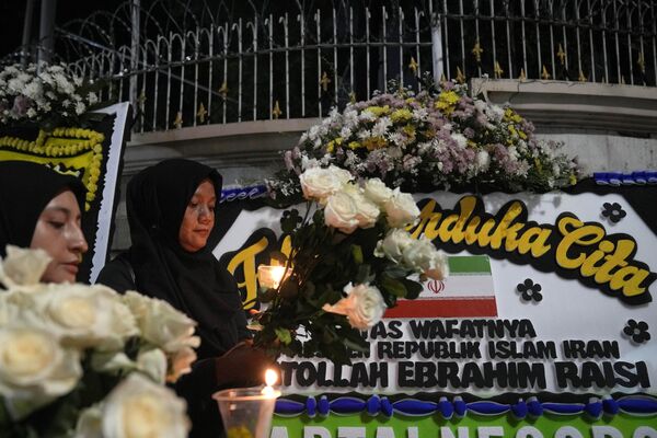 Женщины с цветами в руках посещают церемонию зажжения свечей в память об Ибрахиме Раиси в Джакарте. - Sputnik Таджикистан