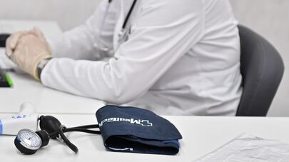 Врач сидит за столом кабинета в поликлинике Москвы.