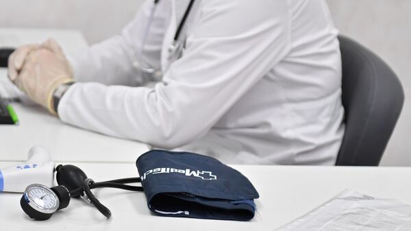 Врач сидит за столом кабинета в поликлинике Москвы. - Sputnik Тоҷикистон