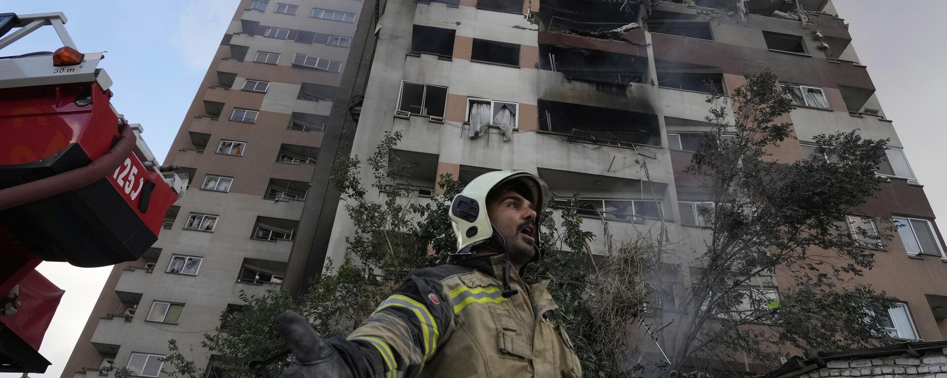 Пожарный на месте взрыва в жилом комплексе на севере Тегерана, Иран  - Sputnik Тоҷикистон, 1920, 15.06.2025