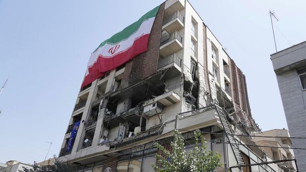 Иранский флаг висит на здании, которое подверглось израильскому удару в Тегеране  - Sputnik Тоҷикистон