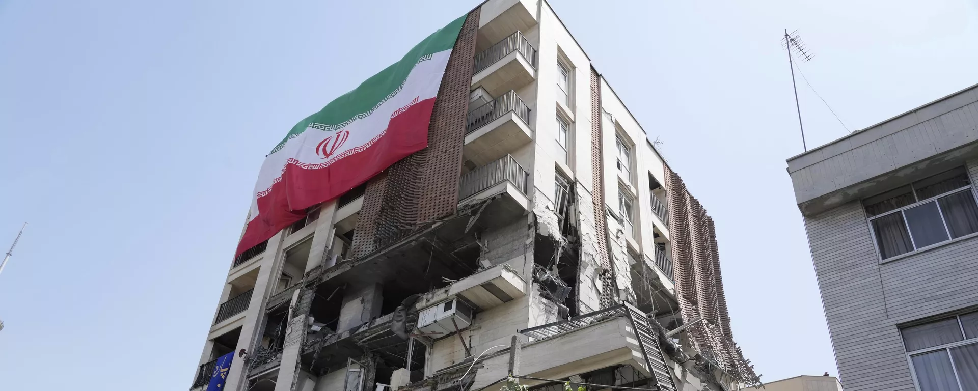 Иранский флаг на здании, которое подверглось израильскому удару в Тегеране — Sputnik Таджикистан, 1920, 28.02.2026