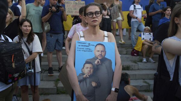 Протестующий держит плакат с изображением президента Владимира Зеленского и Андрея Ермака во время акции протеста против нового законопроекта, в Киеве, Украина, 24 июля 2025 года.  - Sputnik Таджикистан