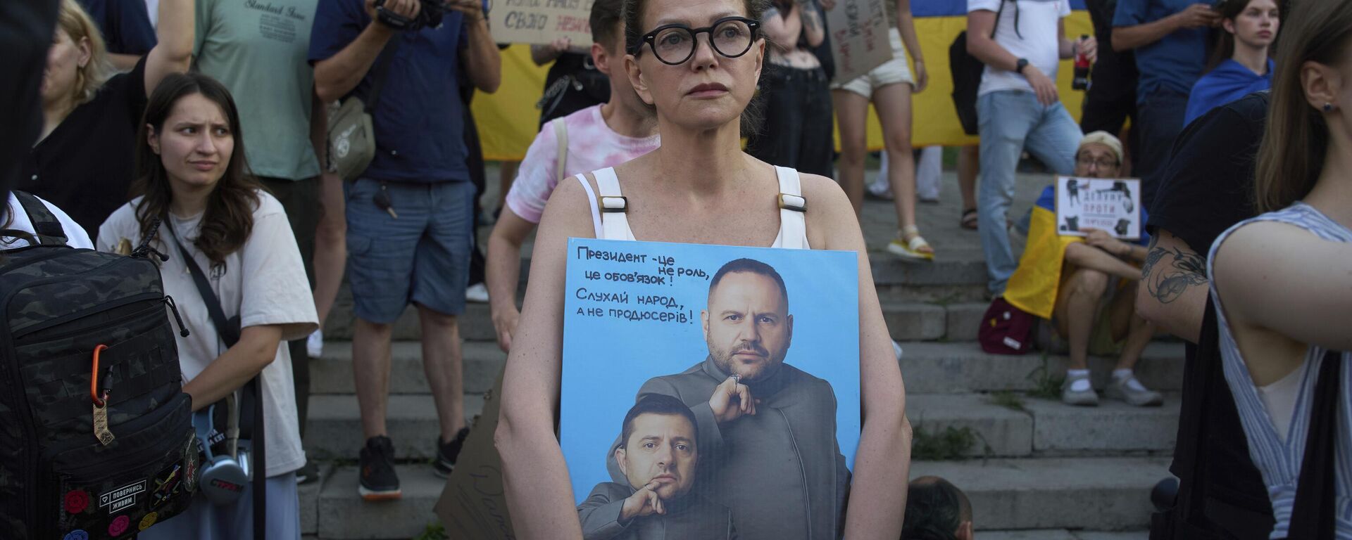 Протестующий держит плакат с изображением президента Владимира Зеленского и главы его президентской канцелярии Андрея Ермака. Архивное фото - Sputnik Тоҷикистон, 1920, 06.11.2025