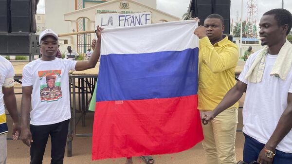 Граждане Нигера держат российский флаг в начале акции протеста, призывающей бороться за свободу страны и противостоять иностранному вмешательству, в Ниамее, Нигер. Архивное фото - Sputnik Таджикистан