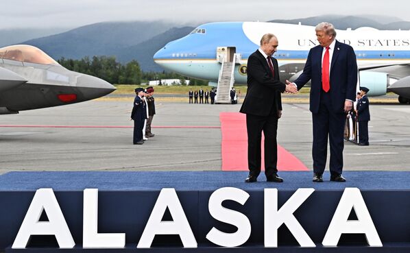Владимир Путин и Дональд Трамп пожимают руки во время встречи на военной базе Эльмендорф-Ричардсон на Аляске. - Sputnik Таджикистан