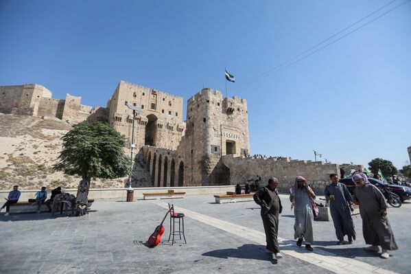 Сайёҳон дар назди қалъаи бостонии Ҳалаби Сурия. Сайёҳон дар назди қалъаи бостонии Ҳалаби Сурия. - Sputnik Тоҷикистон