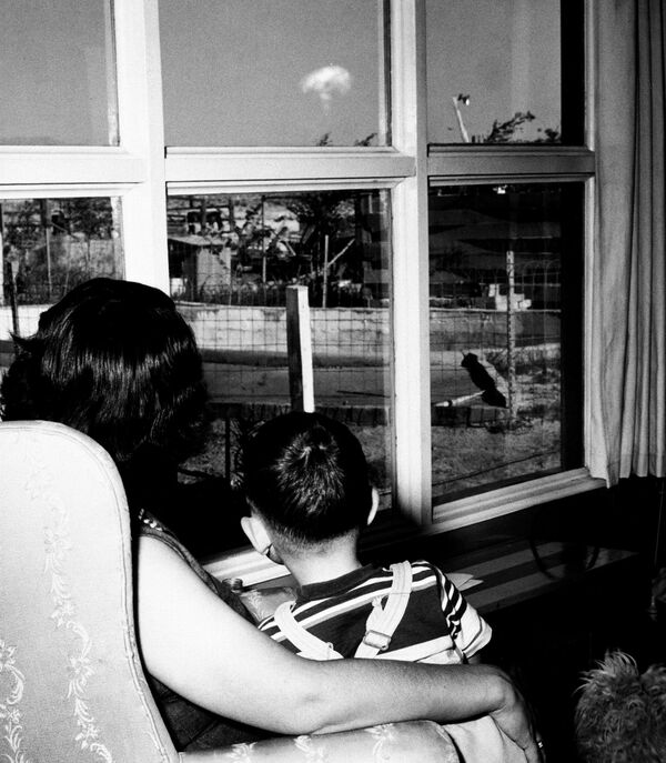 Женщина и маленький мальчик наблюдают за грибовидным облаком от испытательного ядерного взрыва 8 мая 1953 года в гостиной своего дома в Лас-Вегасе. Он произошел в 120 километрах от Невады. Затяжная вспышка указывала на то, что взрыв  был одним из крупнейших в серии. - Sputnik Таджикистан