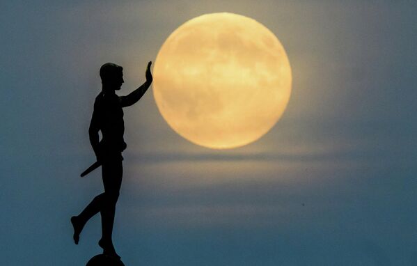 Моҳ дар паси муҷассамаи “Машъалкаш” (1937) дар соҳили кӯли Машзее, Олмон, дар уфуқ тулӯъ мекунад Моҳ дар паси муҷассамаи “Машъалкаш” (1937) дар соҳили кӯли Машзее, Олмон, дар уфуқ тулӯъ мекунад - Sputnik Тоҷикистон