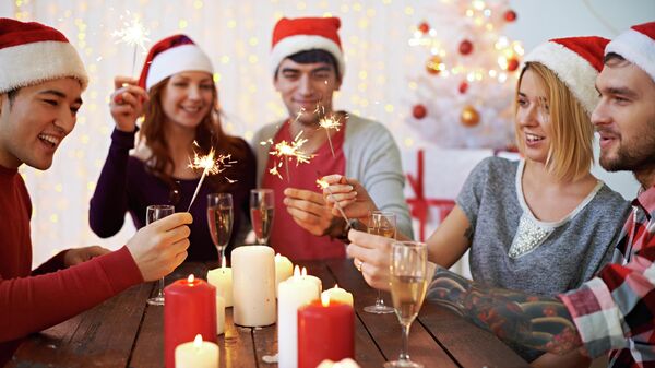 Молодые люди празднуют Рождество с шампанским и бенгальскими огнями  - Sputnik Таджикистан