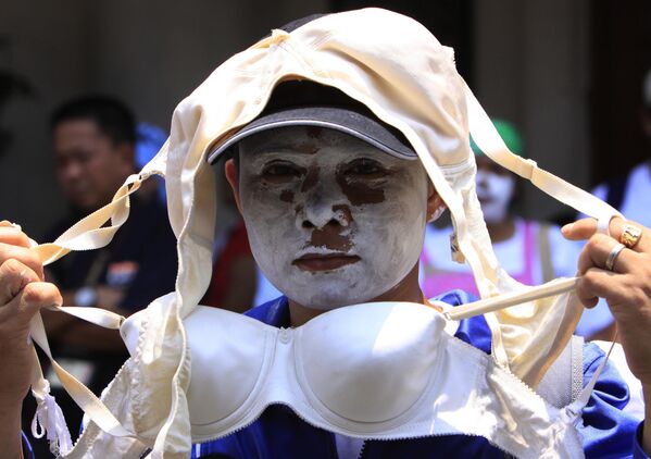 Работница с раскрашенным в белый цвет лицом демонстрирует женский бюстгальтер во время митинга перед зданием Министерства труда во вторник, 30 июня 2009 года, в Маниле, Филиппины. Работницы Triumph International устроили митинг, протестуя против предполагаемого незаконного закрытия немецкой компании, которое привело к увольнению 1600 работников. Работница с раскрашенным в белый цвет лицом демонстрирует женский бюстгальтер во время митинга перед зданием Министерства труда во вторник, 30 июня 2009 года, в Маниле, Филиппины. Работницы Triumph International устроили митинг, протестуя против предполагаемого незаконного закрытия немецкой компании, которое привело к увольнению 1600 работников. - Sputnik Таджикистан