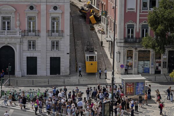 Люди смотрят на сошедший с рельсов и потерпевший аварию туристический трамвай в Лиссабоне. - Sputnik Таджикистан