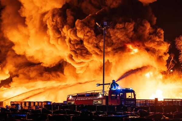 Пожарные тушат пожар на территории компании по переработке пластмасс в промышленной зоне в Алене, Германия. - Sputnik Таджикистан