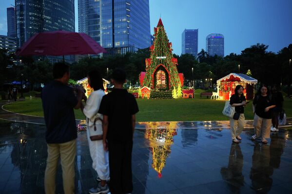 Люди проходят мимо рождественской елки, установленной в парке в Джакарте, Индонезия. - Sputnik Таджикистан