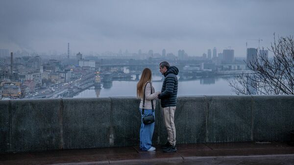 Пара стоит на мосту в Киеве, Украина, понедельник, 1 декабря 2025 года. - Sputnik Таджикистан