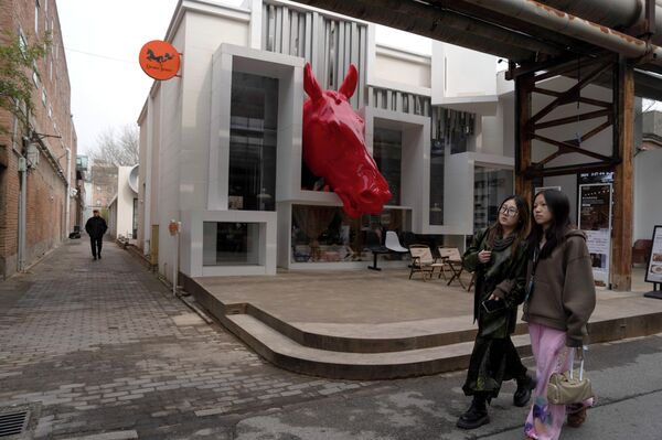 Меҳмонони ноҳияи санъати 798 дар Пекин, марти соли 2024, аз назди тарабхонае мегузаранд, ки дар он ҳайкали бузурги сари асп тасвир шудааст. Меҳмонони ноҳияи санъати 798 дар Пекин, марти соли 2024, аз назди тарабхонае мегузаранд, ки дар он ҳайкали бузурги сари асп тасвир шудааст. - Sputnik Тоҷикистон