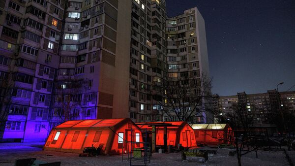 Палатки правительственного пункта гуманитарной помощи рядом с многоквартирными домами во время отключения электроэнергии в Киеве, Украина, 12 января 2026 года. - Sputnik Таджикистан