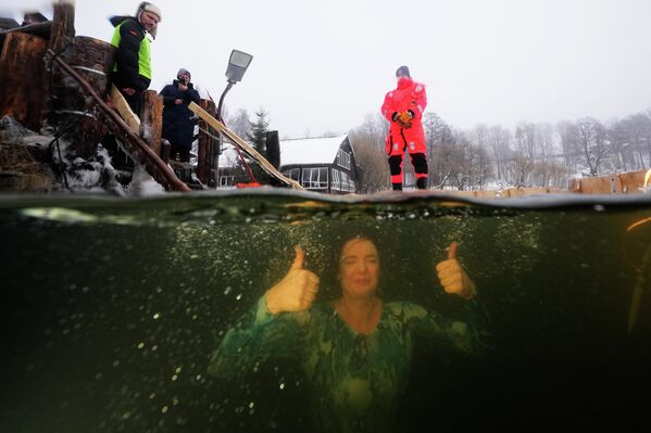 Русская православная верующая купается в ледяной воде в проруби в Санкт-Петербурге в честь праздника Богоявления. - Sputnik Таджикистан