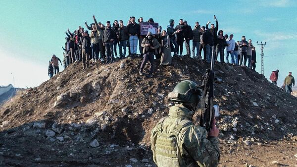 Турецкий солдат охраняет границу, в то время как прокурдские протестующие пытаются пройти к приграничной зоне во время демонстрации в Нусайбине, на юго-востоке Турции - Sputnik Таджикистан