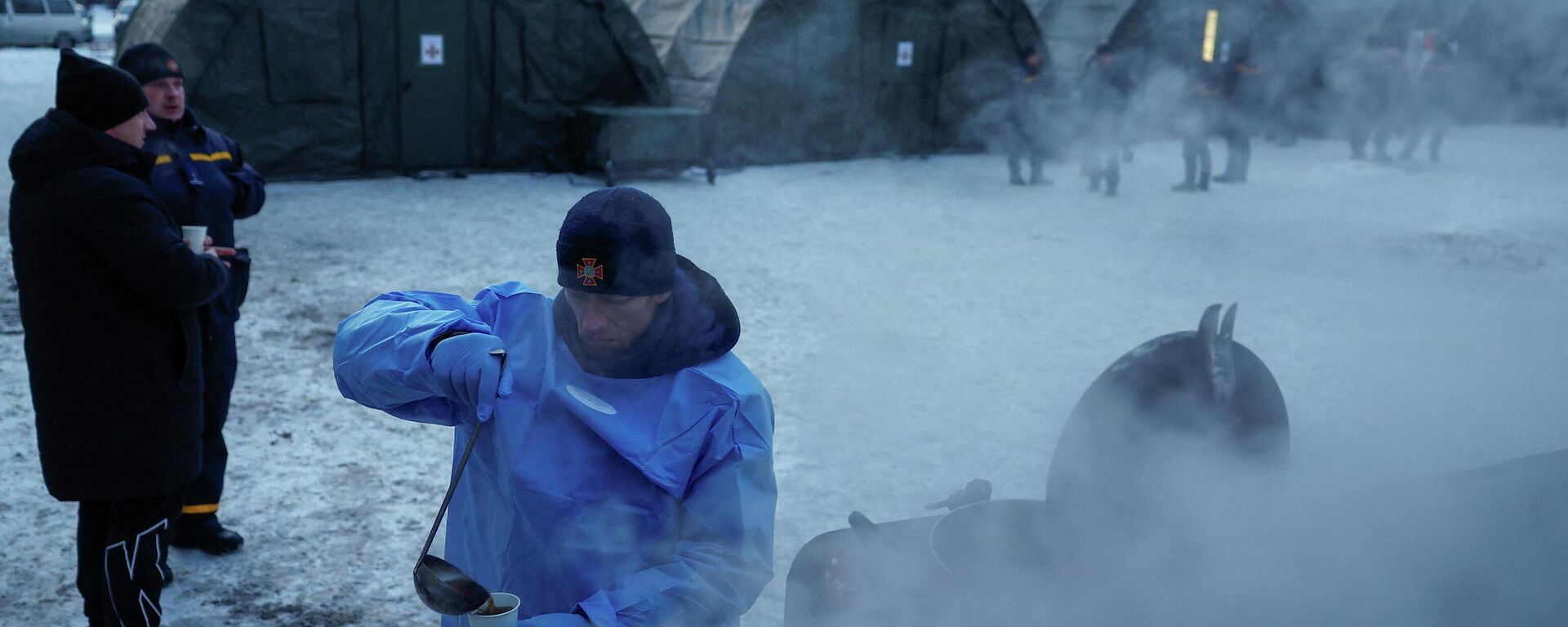 Сотрудник Государственной службы по чрезвычайным ситуациям наливает чай в чашку перед палатками правительственного пункта гуманитарной помощи. Киев, Украина, 25 января 2026 года.  - Sputnik Тоҷикистон, 1920, 04.02.2026