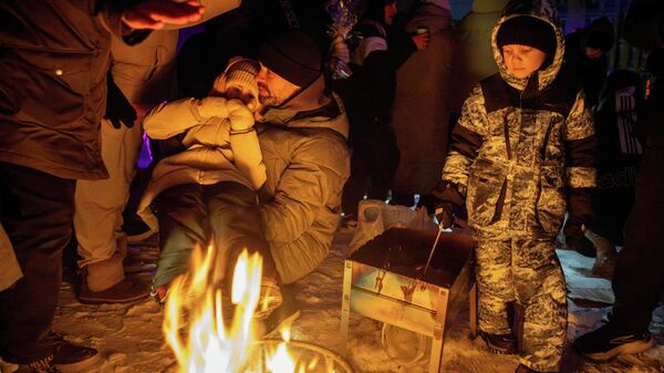 Люди греются у костра во время блэкаута в Киеве, Украина, 24 января 2026 года.  - Sputnik Тоҷикистон