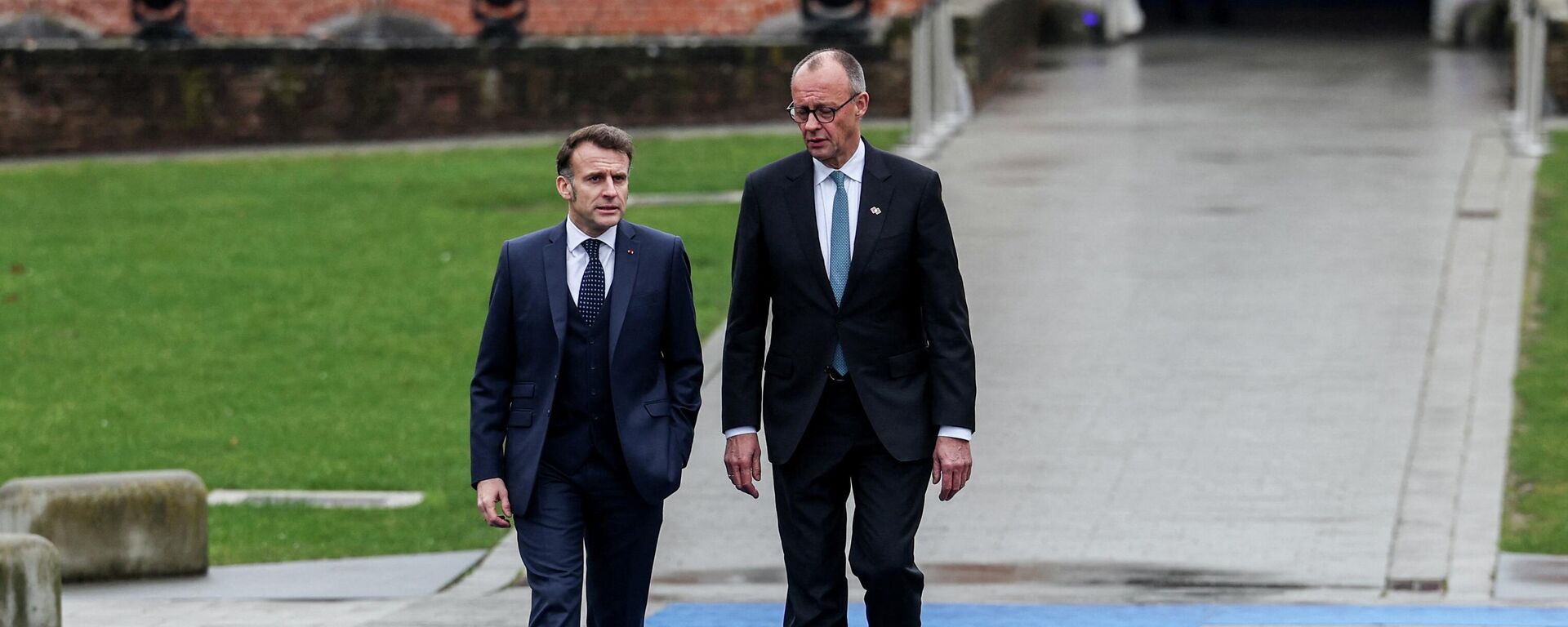 Канцлер Германии Фридрих Мерц и президент Франции Эммануэль Макрон на территории замка Олден-Бизен в день неформальной встречи лидеров Европейского союза, Бельгия, 12 февраля 2026 года.  - Sputnik Тоҷикистон, 1920, 13.02.2026