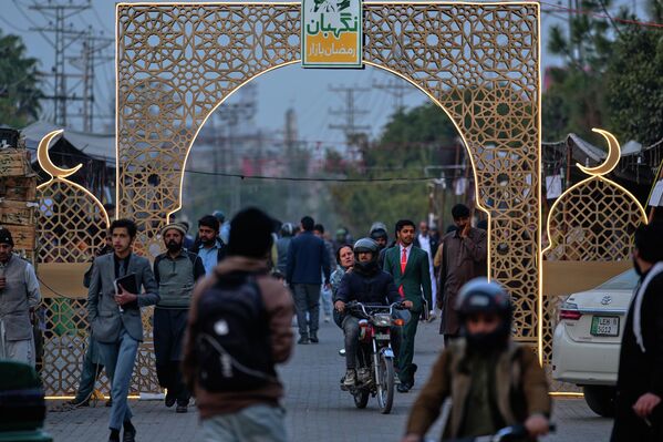 Люди проходят под неоновой инсталляцией, установленной местными властями в связи с предстоящим священным для мусульман месяцем поста Рамадан, в Равалпинди, Пакистан. - Sputnik Таджикистан