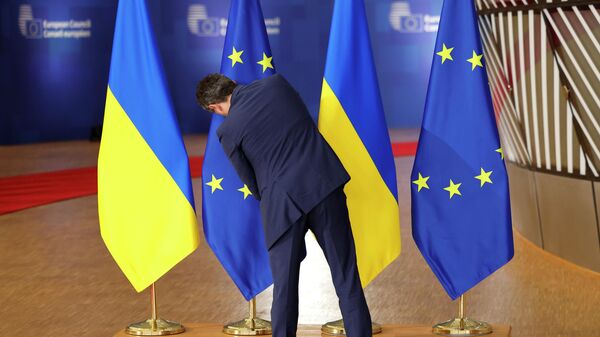 Сотрудник протокола поправляет флаги ЕС и Украины во время саммита ЕС в Брюсселе. Архивное фото - Sputnik Таджикистан