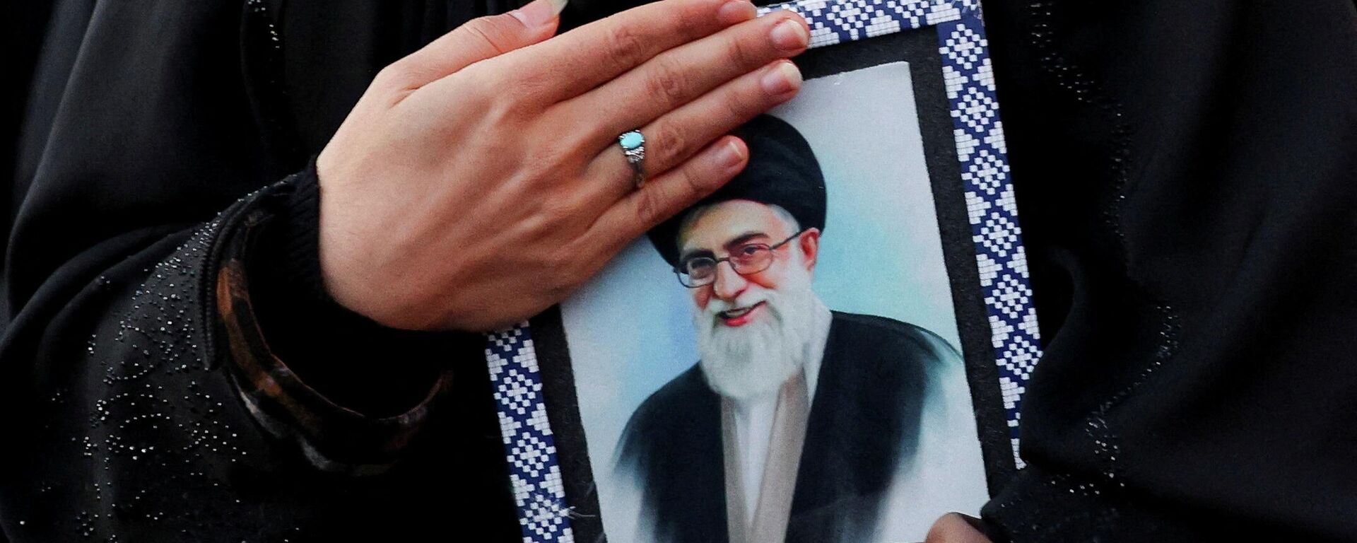 Женщина держит в руках портрет верховного лидера Ирана аятоллы Али Хаменеи на площади Энгелаб, погибшего в результате израильских и американских ударов в субботу в Тегеране, Иран, 1 марта 2026 года. - Sputnik Таджикистан, 1920, 02.03.2026