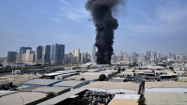 Столб дыма поднимается над складом в промышленной зоне города Шарджа в Объединенных Арабских Эмиратах после иранских ударов в Дубае, Объединенные Арабские Эмираты, воскресенье, 1 марта 2026 года.  - Sputnik Таджикистан