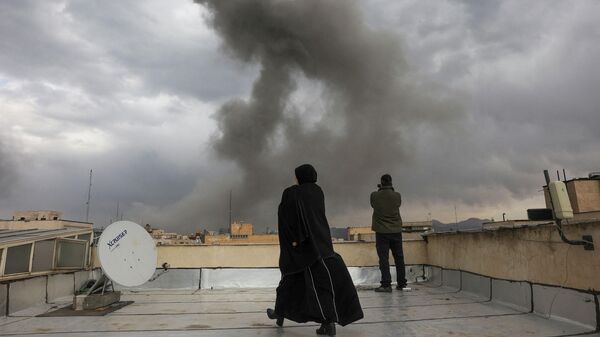 Люди наблюдают за поднимающимся дымом после взрыва, произошедшего после ударов Израиля и США по Ирану  2 марта 2026 года.  - Sputnik Тоҷикистон