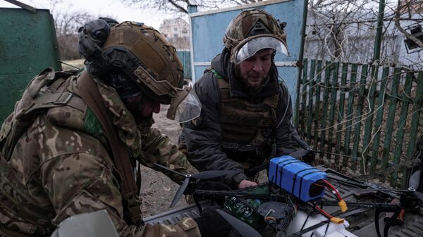 Военнослужащие ударного взвода БПЛА 93-й отдельной механизированной бригады Холодный Яр Вооруженных сил Украины прикрепляют посылку с предметами к беспилотнику с оптоволоконным управлением. - Sputnik Таджикистан