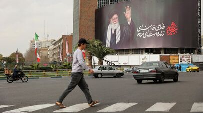 Люди идут мимо рекламного щита с изображением покойного верховного лидера Ирана аятоллы Али Хаменеи на улице после его гибели в результате израильских и американских ударов в субботу в Тегеране, Иран, 2 марта 2026 года.