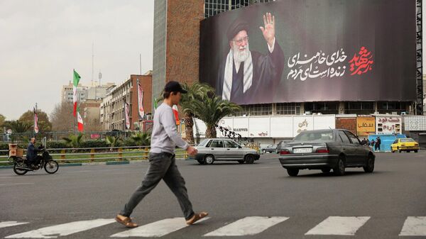 Люди идут мимо рекламного щита с изображением покойного верховного лидера Ирана аятоллы Али Хаменеи в Тегеране, Иран, 2 марта 2026 года. - Sputnik Таджикистан