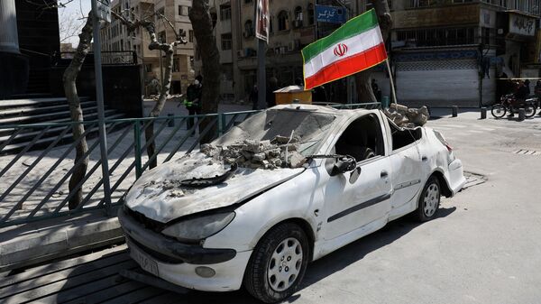 Иранский флаг установлен на поврежденном автомобиле в Тегеране, Иран, 4 марта 2026 года.  - Sputnik Тоҷикистон
