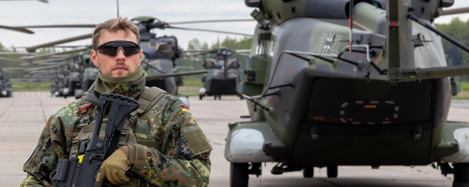 Военный полицейский стоит перед вертолетами ВВС Германии во время военных учений НАТО Griffin Lightning 2025, 6 мая 2025 года.  - Sputnik Таджикистан, 1920, 05.03.2026