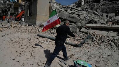 Мужчина несёт иранский флаг, чтобы положить его на обломки полицейского участка, пострадавшего во время американо-израильского удара в Тегеране, Иран, среда, 4 марта 2026 года.