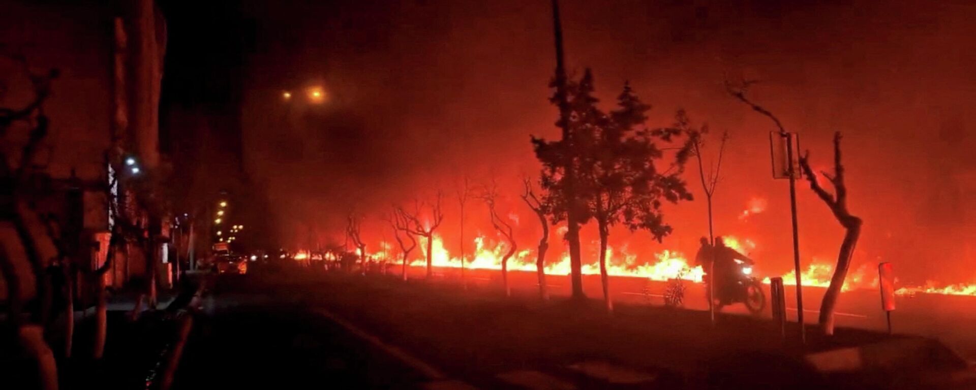 Мотоцикл проезжает мимо горящего бульвара Кохсар в Тегеране, Иран. - Sputnik Таджикистан, 1920, 13.03.2026