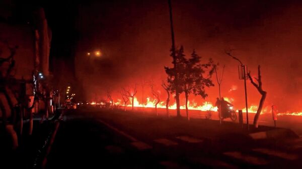 Мотоцикл проезжает мимо горящего бульвара Кохсар в Тегеране, Иран.  - Sputnik Тоҷикистон