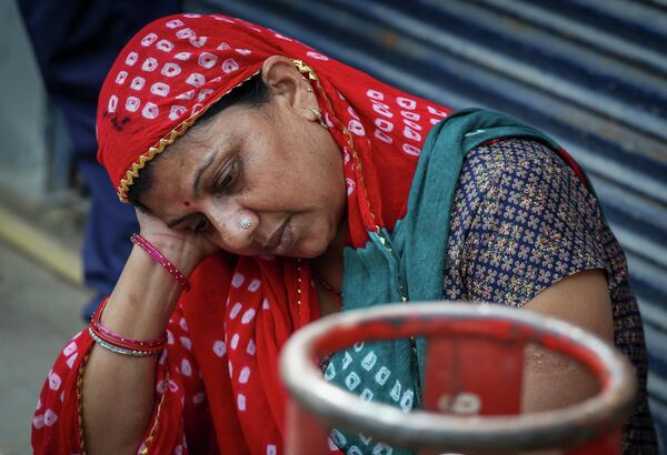 Женщина сидит рядом с пустым газовым баллоном на фоне перебоев в поставках после атак США и Израиля на Иран. - Sputnik Таджикистан