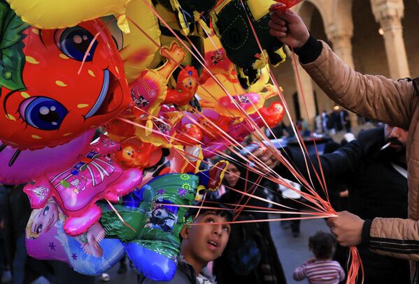 Мальчик рассматривает воздушные шарики, продаваемые торговцем, в то время как верующие собираются у мечети Мухаммеда аль-Амина после молитвы по случаю Ид аль-Фитр, знаменующей окончание священного месяца Рамадан, после эскалации конфликта между Хезболлой и Израилем на фоне американо-израильского конфликта с Ираном, в Бейруте, Ливан - Sputnik Таджикистан