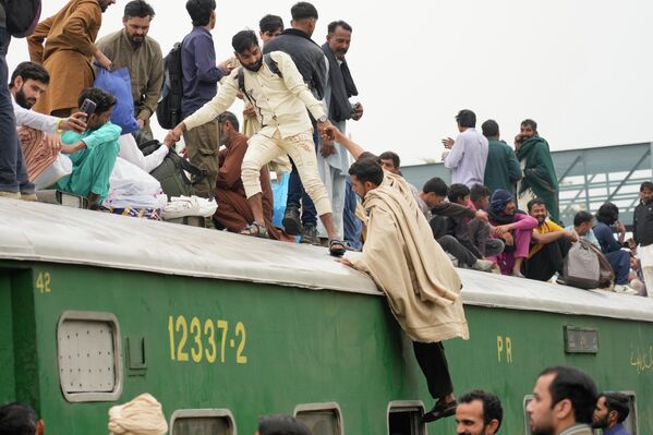 На железнодорожной станции в Лахоре, Пакистан, в четверг, 19 марта 2026 года, люди садятся в переполненный пассажирский поезд, чтобы добраться до своих домов накануне праздника Ид аль-Фитр, знаменующего окончание священного исламского месяца поста Рамадан - Sputnik Таджикистан