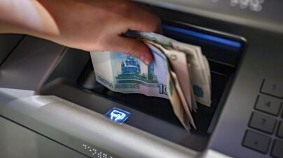 Посетитель кладет деньги на банковский счет в банкомате.