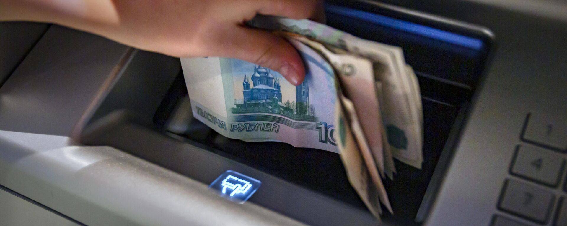Посетитель кладет деньги на банковский счет в банкомате. - Sputnik Тоҷикистон, 1920, 23.04.2026