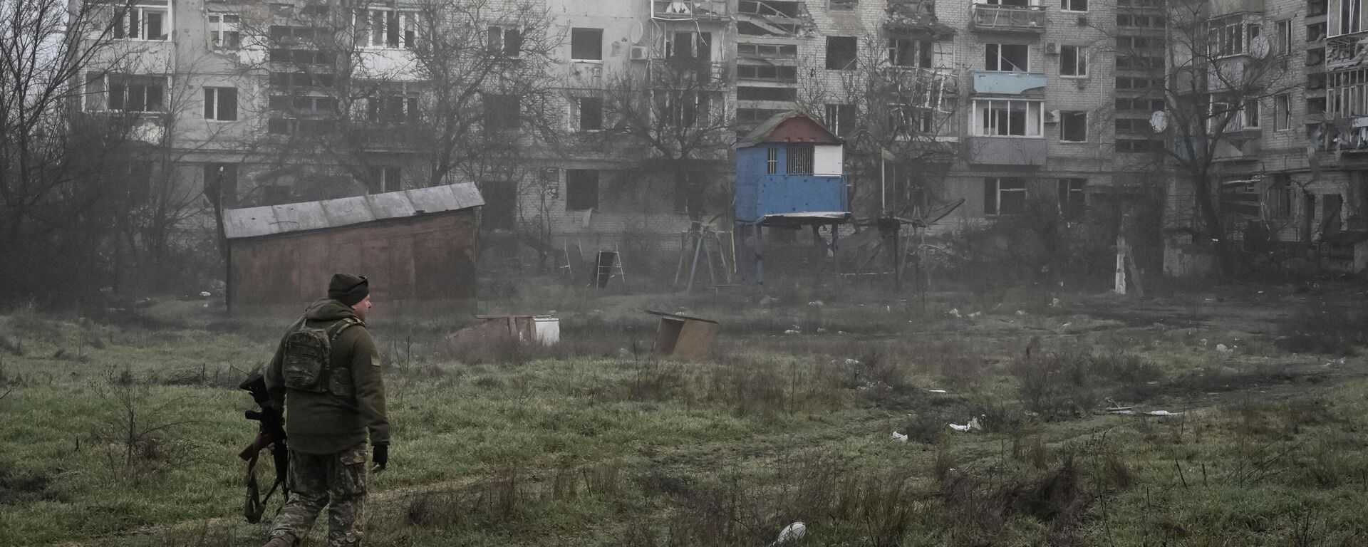 Украинский военнослужащий идет мимо жилых домов в прифронтовом городе Орехов Запорожской области, Украина, 26 марта 2026 года. - Sputnik Таджикистан, 1920, 31.03.2026