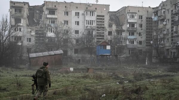 Украинский военнослужащий идет мимо жилых домов в прифронтовом городе Орехов Запорожской области, Украина. - Sputnik Тоҷикистон