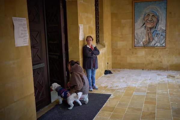 Католичка стоит на коленях рядом со своей собакой у входа в церковь в Ливане. — Sputnik Таджикистан